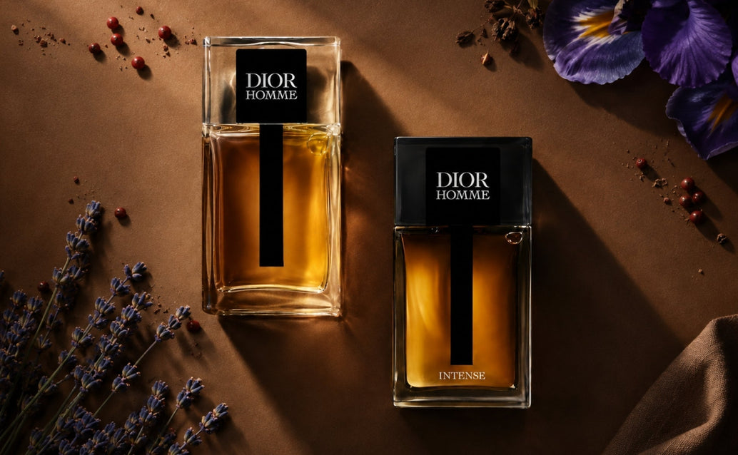 Dior Homme and Dior Homme Intense fragrance bottles arranged on a matte brown surface with iris, lavender, and pink pepper accents under dramatic directional lighting.