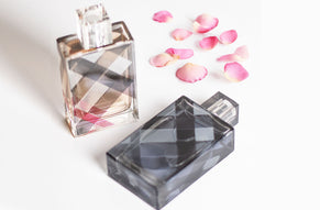 Burberry perfume bottles with signature check pattern design, styled with scattered pink rose petals.