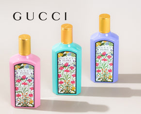Three vibrant Gucci Flora perfume bottles in pink, turquoise, and lavender, each adorned with a floral label and gold cap, elegantly arranged against a neutral background with the Gucci logo displayed above.
