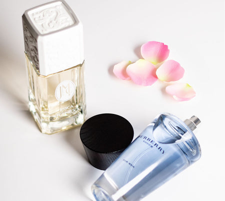 Jessica McClintock and Burberry Touch perfume bottles displayed on a white surface with scattered pink rose petals.