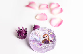 Frozen-themed kids' perfume bottle with Elsa and Anna design, purple crown-shaped cap, and pink rose petals in the background.
