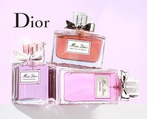 A luxurious display of three Miss Dior perfume bottles in shades of pink, elegantly arranged with delicate bows, set against a soft pastel background with the Dior logo in bold black text.