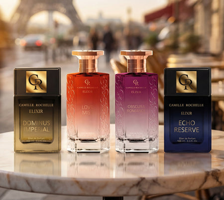 Four Camille Rochelle perfume bottles displayed on a marble table with a blurred Paris backdrop.
