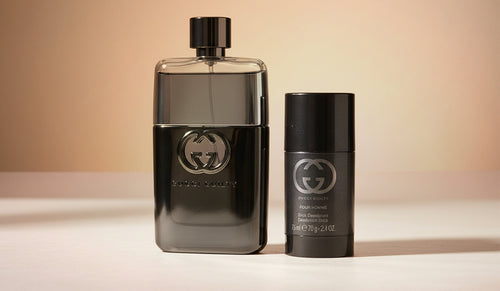 Gucci Guilty cologne and deodorant gift set on a warm beige background.