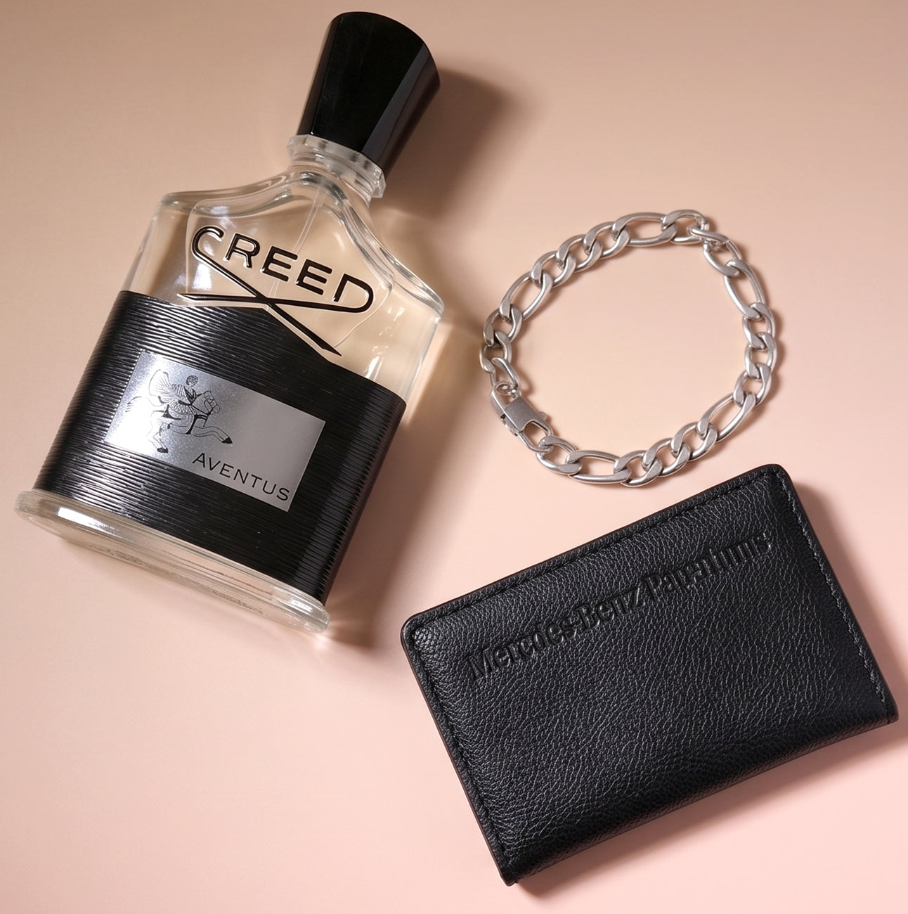 Creed Aventus cologne styled with a silver chain and black leather wallet.