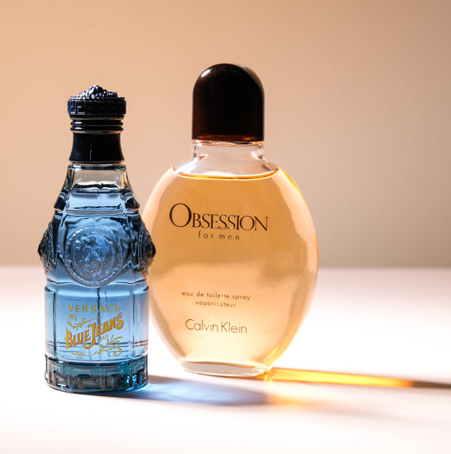 Versace Blue Jeans and Calvin Klein Obsession colognes on a warm beige background.