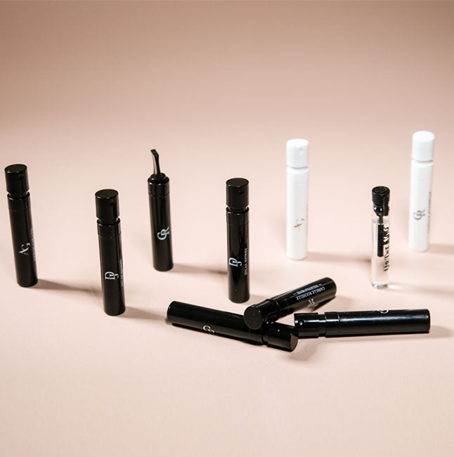 Discovery-size fragrance vials arranged on a warm beige background.