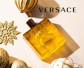 Versace Eros Energy perfume bottle surrounded by gold ornaments and festive holiday decorations.